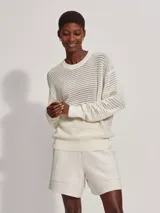 Sweater de punto calado color crema, de corte holgado y cuello redondo.