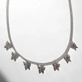 Collar plateado con cadena de eslabones pequeños y siete dijes de mariposas cubiertos de cristales.
