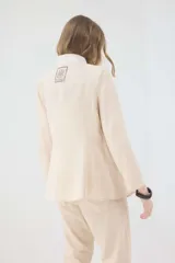 Chaqueta de lino marrón con cuello mao en contraste negro, cierre frontal con botones y hombreras.