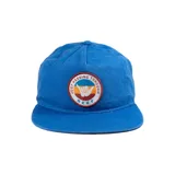 Gorro azul con visera, con parche circular con el logo de Reef y la frase "Just Passing Through".