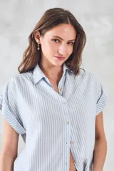 Blusa de viscosa rayada en blanco y celeste, con cuello camisero, mangas cortas con dobladillo y botones frontales.