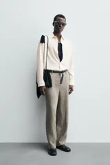 Camisa de hombre de corte relajado (relaxed fit) en tejido de mezcla de algodón y viscosa, color beige claro con finas rayas verticales. Presenta cuello italiano y manga larga con puño abotonado.