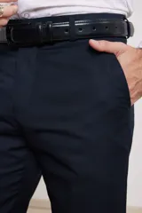 Pantalón de vestir azul marino, de corte recto, con bolsillos laterales y traseros. Se ajusta a la cintura con cinturón de cuero negro.