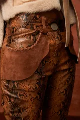 Pantalón acampanado de cuero sintético con estampado de piel de serpiente en tonos azules.