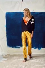 Camisa color naranja de lino o algodón con cuello clásico, cierre frontal con botones y mangas largas con puños abotonados. Presenta un bolsillo de cuero marrón en el pecho.