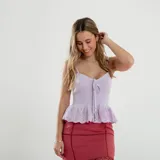 Top color lila de tejido de punto acanalado, con breteles finos y escote en V con lazo ajustable. Tiene detalle de puntilla calada en el ruedo.