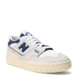 Championes urbanos New Balance modelo 550, con diseño de corte bajo inspirado en el básquet. Presentan una combinación de cuero y malla en tonos beige y azul marino, con suela de goma en tono crema envejecido.