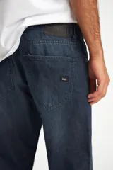 Pantalón de jean azul oscuro, corte recto, con ruedo doblado.