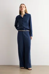 Pantalón de corte recto y tiro medio, confeccionado en tejido negro de textura sutil. Presenta un diseño minimalista con cierre frontal oculto y caída fluida.