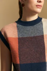 Chaleco tejido de punto con diseño de bloques a cuadros en tonos rosados, marrones y beige. Presenta cuello redondo y terminaciones acanaladas en cuello y sisas.