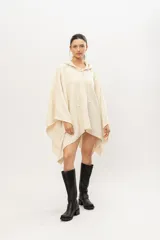 Poncho tejido en telar en 100% lana merino color crudo, con capucha y cordones de ajuste.