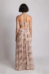 Top corto negro con estampado floral blanco, con parte delantera ajustable mediante cordones y fruncido. Tirantes elásticos y botones metálicos en la espalda.