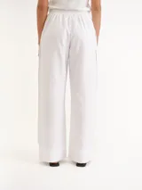 Pantalón blanco de lino con diseño de corte recto y amplio, bolsillos laterales superpuestos y cintura elástica.