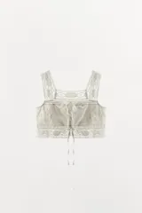 Top crop de algodón con escote cuadrado y tirantes anchos. Presenta bordados florales, aplicaciones de encaje y cierre frontal con botones y lazadas.
