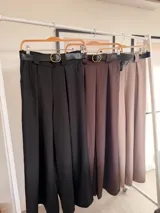 Pantalón de vestir color marrón chocolate, de corte ancho y tiro alto, con pinzas frontales y cinto negro con hebilla dorada incluido.