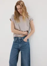 Jeans estilo wide leg de tiro medio con diseño de cinco bolsillos, trabillas para cinturón, cierre de botón y cremallera, y bajo vuelto.