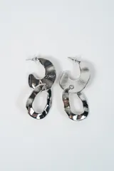 Aros colgantes de diseño moderno con acabado metálico plateado, compuestos por dos piezas irregulares entrelazadas con textura martillada.