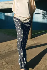 Pantalón de tiro medio con cintura elástica y bolsillos ocultos en costura. Presenta un diseño de corte recto con dobladillo ancho en el bajo y un estampado geométrico sobre fondo oscuro.