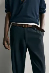 Pantalón chino negro slim fit de corte recto, con bolsillos frontales, trabillas para cinturón y cierre frontal con cremallera y botón.