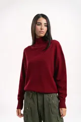 Polera de lana de corte holgado, con cuello alto tejido y mangas largas con caída de hombro.