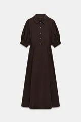 Vestido midi de algodón con cuello solapa, cierre frontal con botones y mangas cortas abullonadas con puños. Presenta un diseño evasé con bolsillos laterales ocultos y elástico en la espalda.