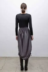 Top negro de mangas largas con frunces en el hombro izquierdo.