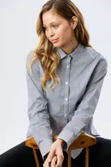 Camisa de manga larga con diseño de rayas verticales, confeccionada en mezcla de algodón, nylon y spandex. Cuenta con cuello camisero clásico y cierre frontal abotonado.