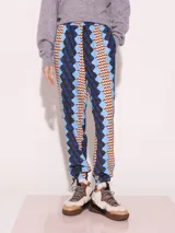 Pantalón con estampado geométrico en tonos azul, celeste, marrón y verde. Tiene cintura y tobillos elastizados con tancas para regular.