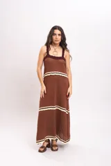 Vestido largo de tejido de punto color marrón, con tirantes anchos, escote cuadrado con detalles en tono bordó y franjas horizontales en color crema con terminación ondulada.