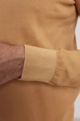 Polera de punto color tostado, de corte ajustado, mangas largas tipo raglán y cuello alto acanalado.