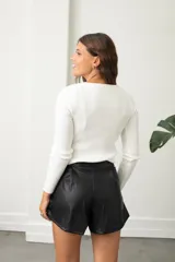 Polera de morley blanco con cuello redondo y detalle de tiras cruzadas en el escote, de manga larga y ajuste al cuerpo.