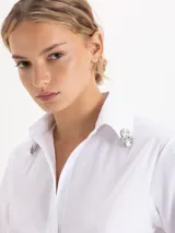 Camisa de algodón con lycra en color celeste claro, de corte clásico y manga larga. Presenta apliques de piedras de cristal en las puntas del cuello y una cartera oculta con botones.