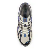 Championes New Balance modelo 1906R, de color beige con detalles en azul, negro, gris y amarillo.