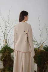 Sweater beige de tejido de punto acanalado con cuello redondo y mangas largas. Presenta apliques de manchas de colores en el frente y las mangas.