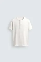 Camiseta blanca de manga corta con cuello redondo y tapeta de botones frontal (cuello panadero o henley).