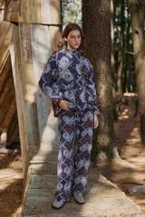 Campera de abrigo con cuello alto y manga ranglan, confeccionada en tela capitoneada con relleno y forro interno. Presenta un diseño estampado con motivos geométricos y paisley en tonos azules y marrones.