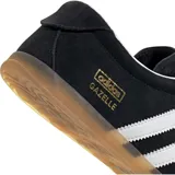 Championes Adidas modelo Gazelle Lo Pro, color negro con las icónicas tres tiras laterales en blanco. Presenta un diseño de perfil bajo con capellada de gamuza, interior en contraste blanco y suela de goma color caramelo. Incluye el logo de la marca y el nombre del modelo en dorado en el lateral.