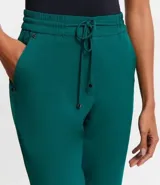 Pantalón de vestir femenino color marrón oscuro, de corte fluido y tiro medio/alto, con cintura elástica ajustable mediante cordón. Presenta bolsillos laterales y cierre frontal.