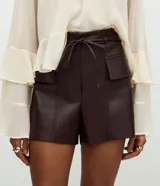 Short de poliuretano color marrón oscuro, con cintura fruncida en la parte trasera, bolsillos delanteros amplios con solapas estructuradas y acabado brillante.