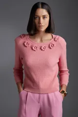 Sweater de punto color rosa con cuello redondo y apliques de flores en el escote.