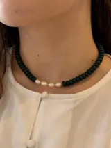Gargantilla corta compuesta por cuentas cilíndricas de vidrio en color verde oscuro y un sector central con perlas de río naturales de forma irregular separadas por pequeños abalorios dorados.