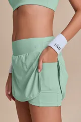 Pollera deportiva color rosa fucsia, con estampado en relieve de texto. Es de corte corto con ruedo redondeado y cuenta con shorts internos.