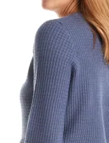 Cardigan de punto color fucsia, con escote a la base, cierre frontal con botones metálicos dorados y terminaciones desflecadas. Presenta bolsillos simulados en la parte delantera y mangas largas.