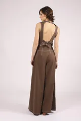 Pantalón marrón de corte palazzo, tiro alto, con pliegues frontales y pespuntes blancos decorativos.