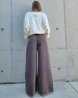 Pantalón de jean color beige, de corte recto y tiro alto, con ruedo deshilachado y cierre frontal con botón y cremallera.