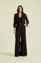 Pantalón negro de tiro alto y corte amplio tipo palazzo, con bolsillos laterales y cierre con cinturón con hebilla metálica dorada.