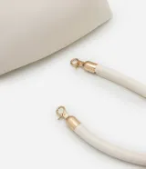 Cartera shoulder de poliuretano color crema, con asa corta de mano y asa larga de cadena dorada, ambas removibles. Incluye cierre de cremallera y borla decorativa.