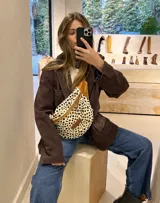 Riñonera con estampado animal, con detalles en cuero color chocolate y correa regulable.