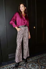 Pantalón palazzo estampado arabesco en tonos beige y negro, con cintura elástica y cinturón negro con hebilla dorada.