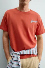 Camiseta de corte relajado con cuello redondo y manga corta. Presenta un estampado frontal con texto en contraste y un acabado con efecto lavado que le otorga una apariencia única.